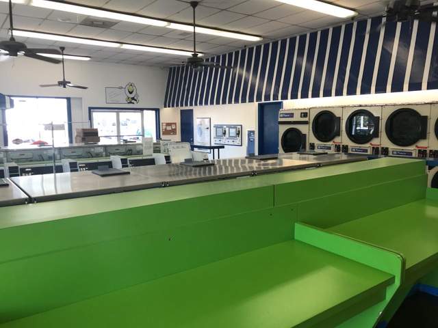 Washers and Dryer. Long table. Clean green counter. Ceiling fans.