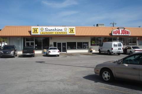 Exterior with parking lot. Sunshine Laundry sign - open 24 hours. Next to Papa John's Pizza.