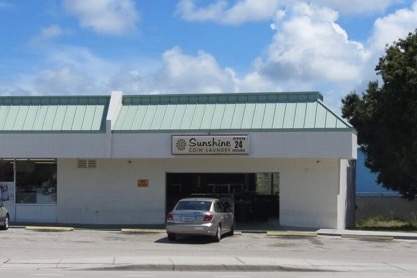Exterior of Sunshine Laundry. Sign - 24 hours. Parking lot.