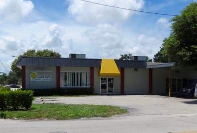 Exterior of building and parking lot. Yellow awning.