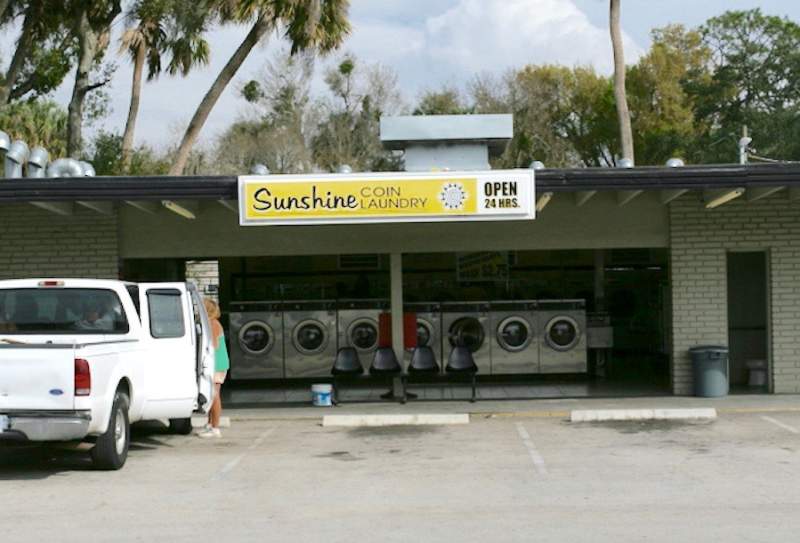 Okeechobee Parrot Avenue Location. Exterior and parking lot. Sign: Sunshine Coin Laundry.